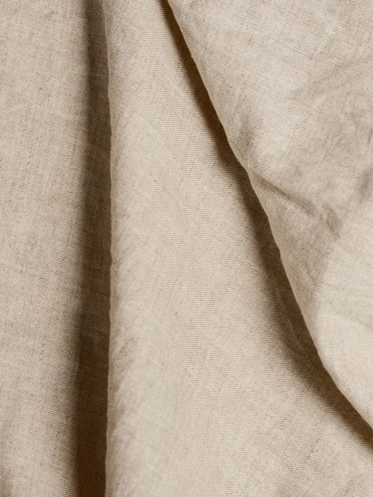 Folded oat-coloured linen with visible hand-stitched hem.